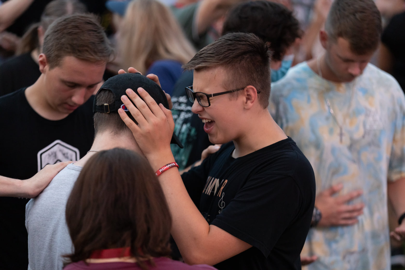 Young people laying hands and praying for healing